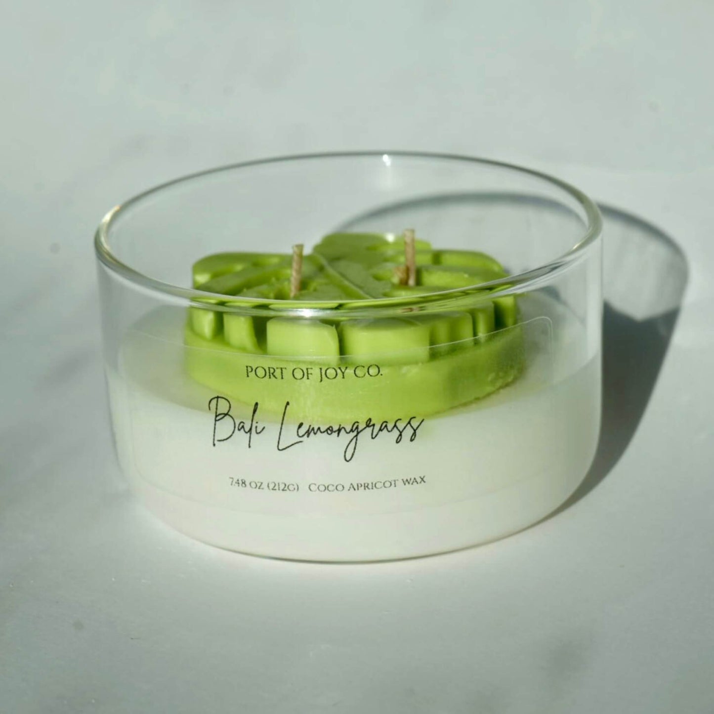 bali lemongrass scented candle, contain in a lear glass jar with unique leaf on top embedded.