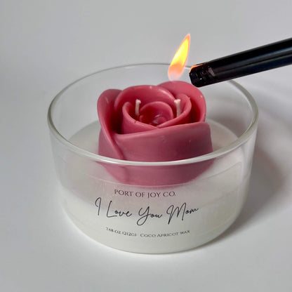 Rose-shaped candle being lit in a glass jar with 'Port of Joy Co.' branding.