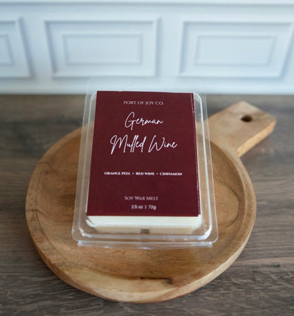 A packaged wax melt from Port of Joy Co. labeled 'German Mulled Wine' sits on a round wooden serving board.