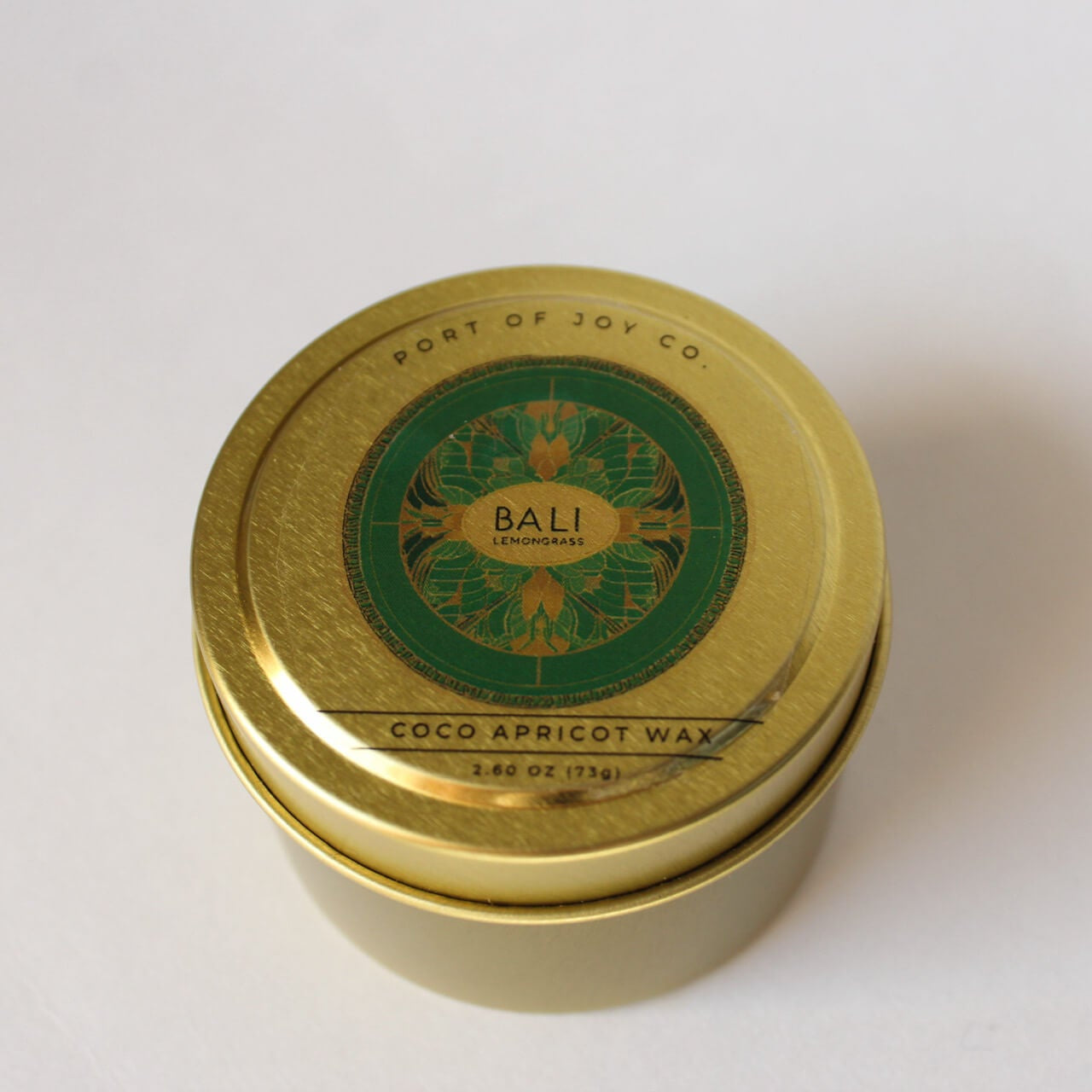 Gold candle tin with green label on a white background