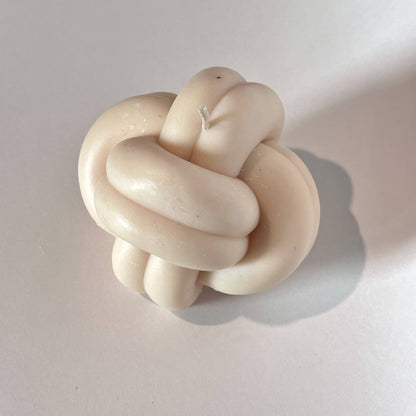 Beige knot-shaped object on a light gray background