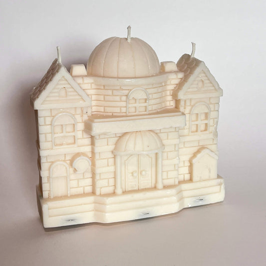 Candle shaped like a castle with a dome on a plain background