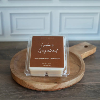 A packaged wax melt product labeled 'Londoner Gingerbread' by Port of Joy Co, placed on a round wooden serving board