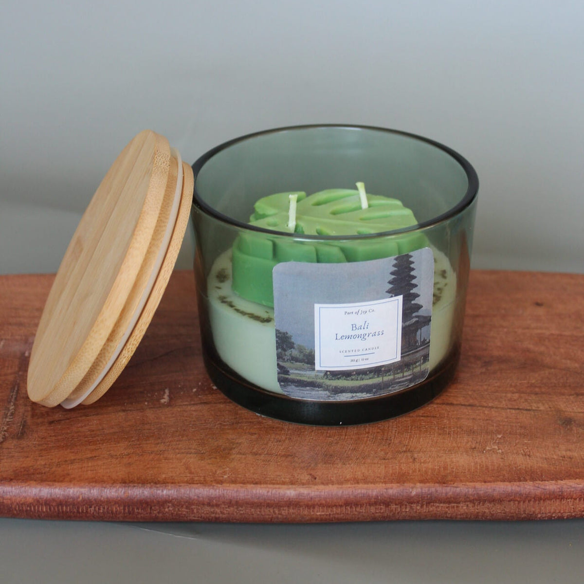 Green big coconut wax candle in a glass jar with a wooden lid on.