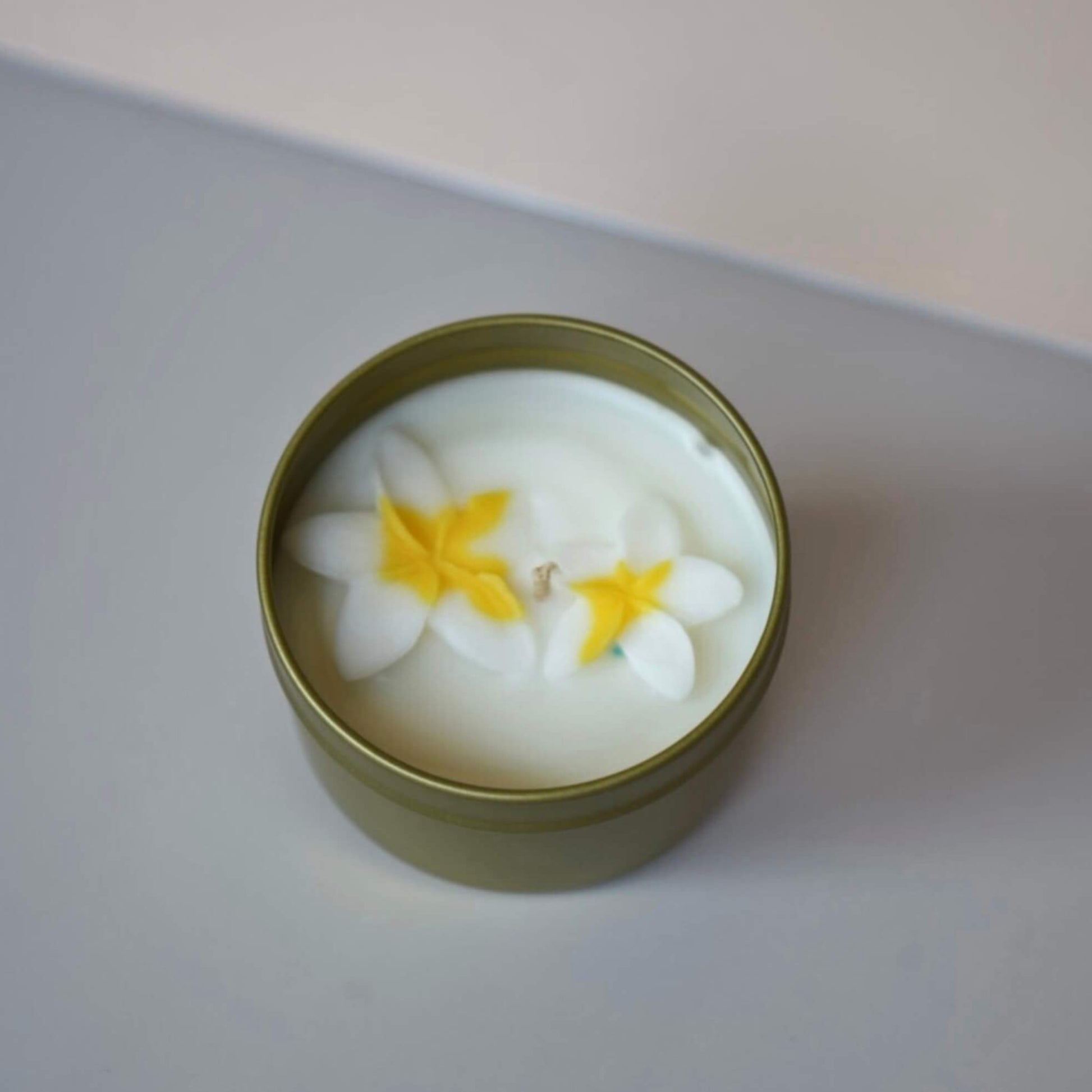 Candle in a tin with floral design on a neutral background
