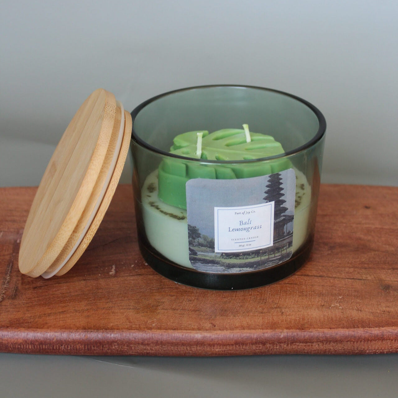 Green candle in a glass jar with a wooden lid on a wooden surface.perfect gift for women and friends