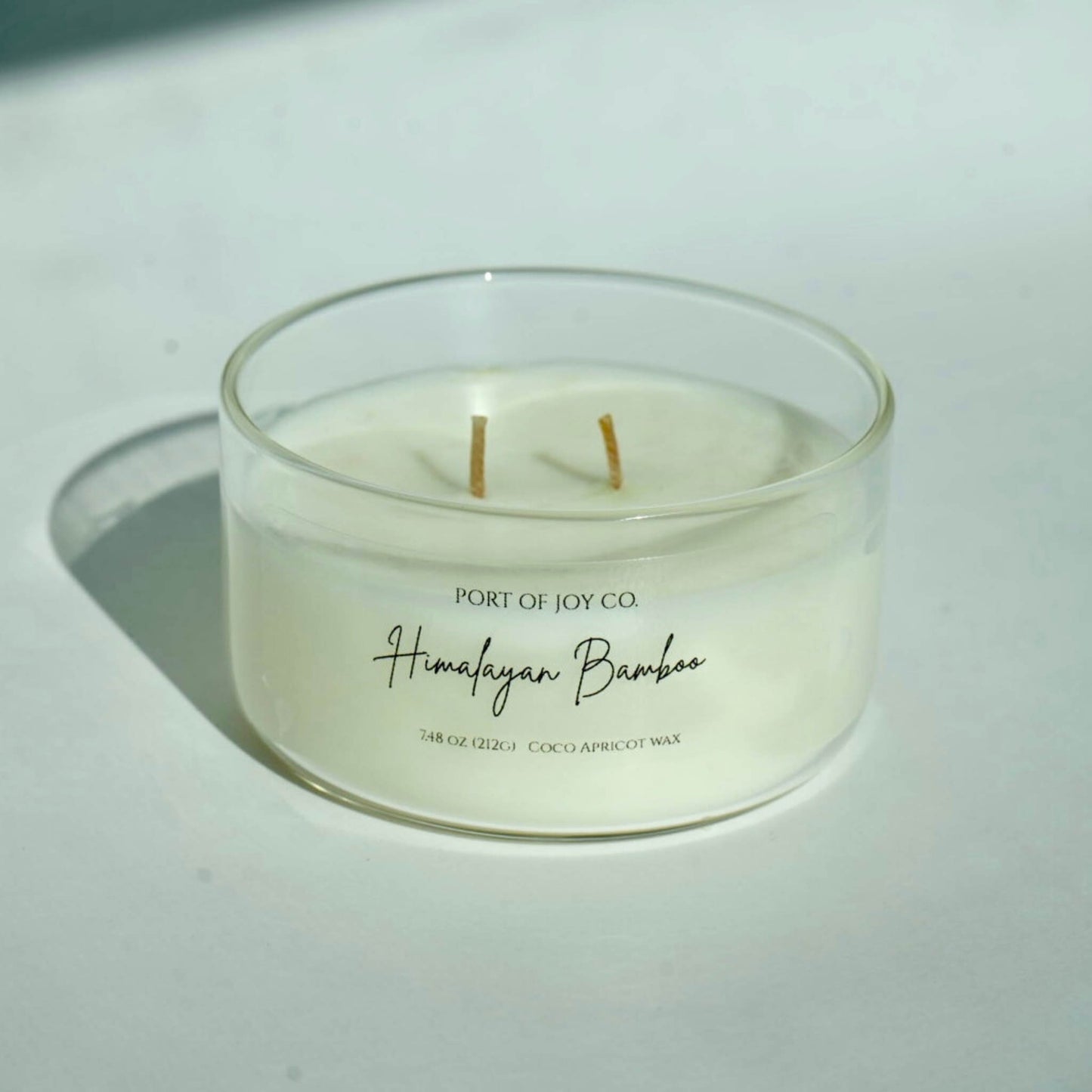Candle in a glass jar labeled 'Himalayan Bamboo' from Port of Joy Co. on a light background
