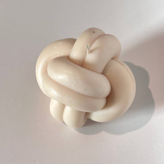Beige knot-shaped candle on a light background