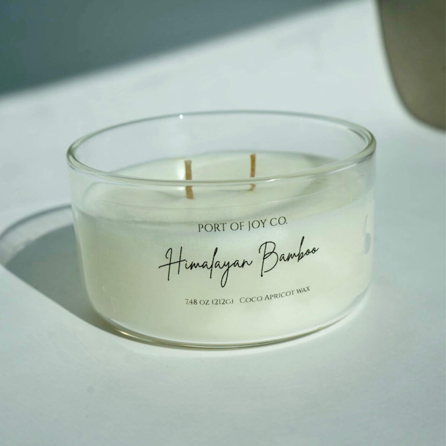 Candle in a glass jar labeled 'Port of Joy Co. Himalayan Bamboo' on a light surface.