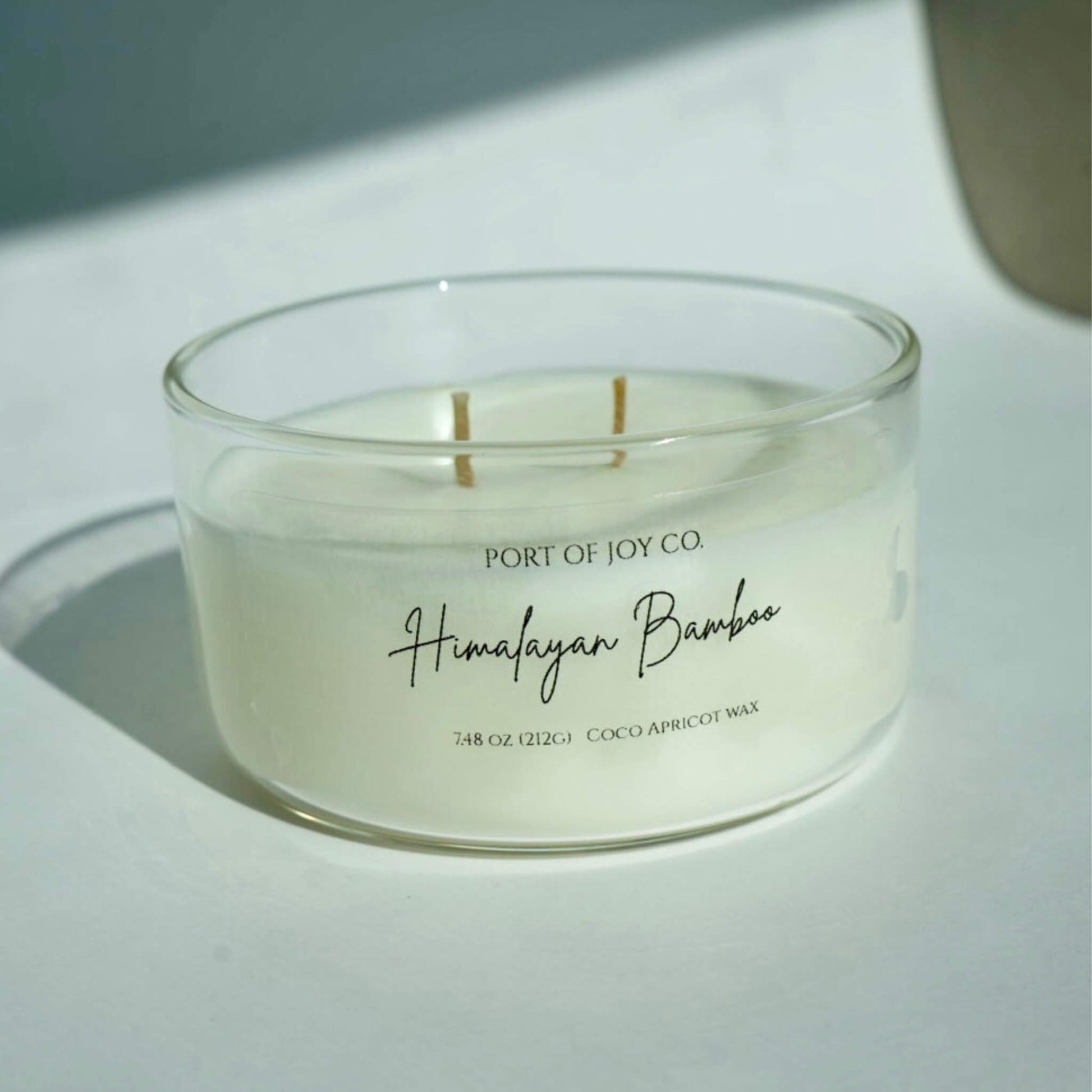 Candle in a glass jar labeled 'Port of Joy Co. Himalayan Bamboo' on a light surface.
