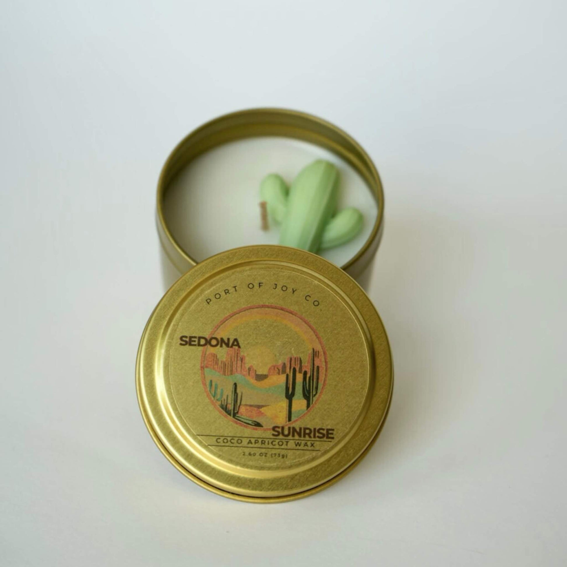 Candle in a gold tin with 'Port of Joy Co' branding on a white background