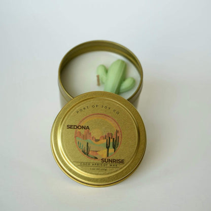 Candle in a gold tin with 'Port of Joy Co' branding on a white background