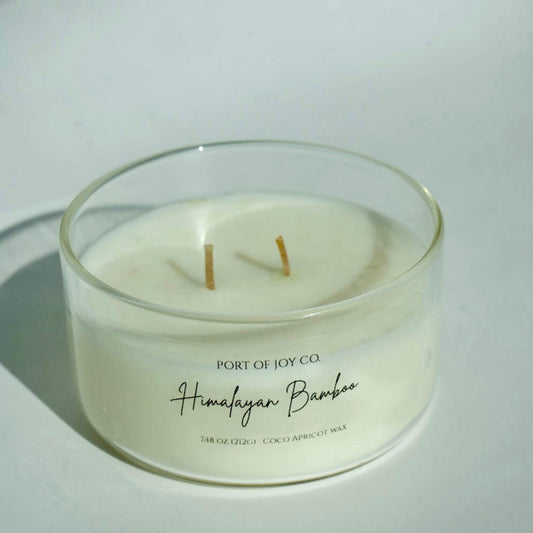 White candle in a glass container with 'Port of Joy Co.' branding on a light background