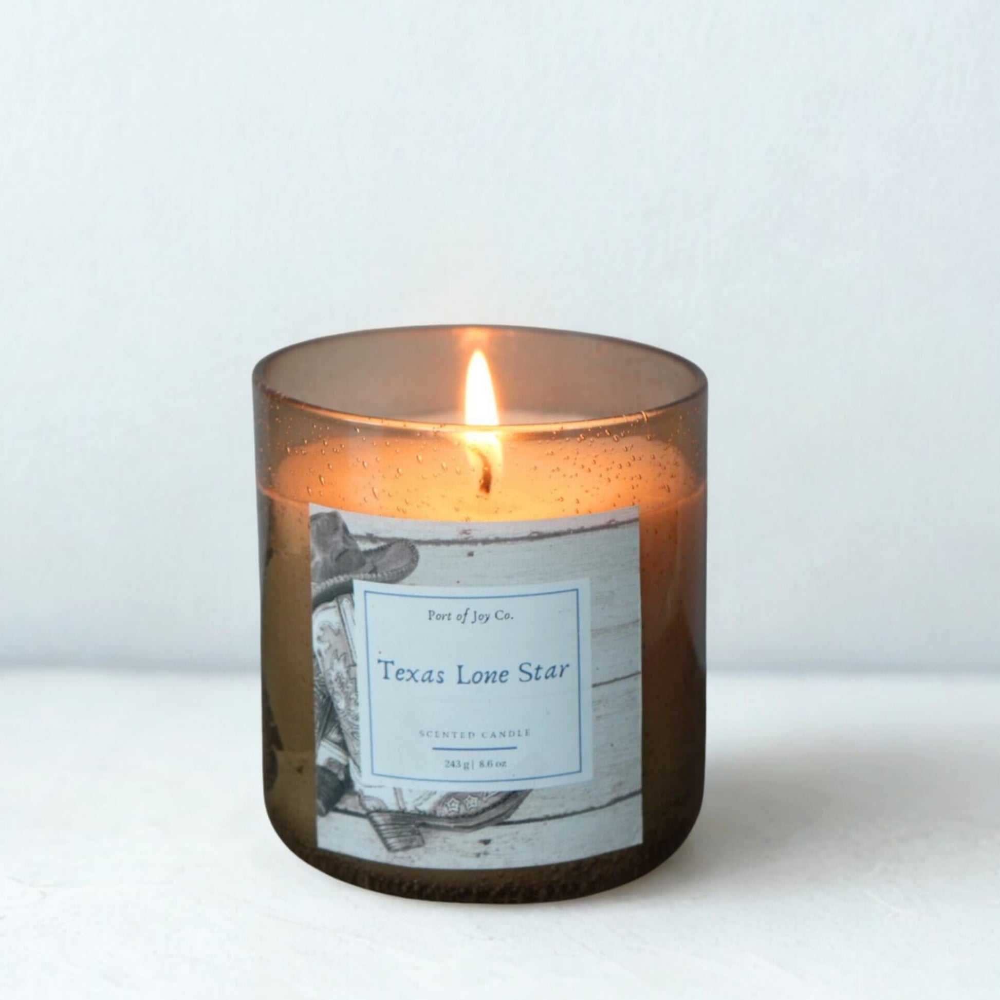 Candle in a brown glass jar with a label on a white background