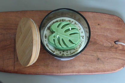 coconut apricot wax Candle with green leaf-shaped embed on a wooden board. 