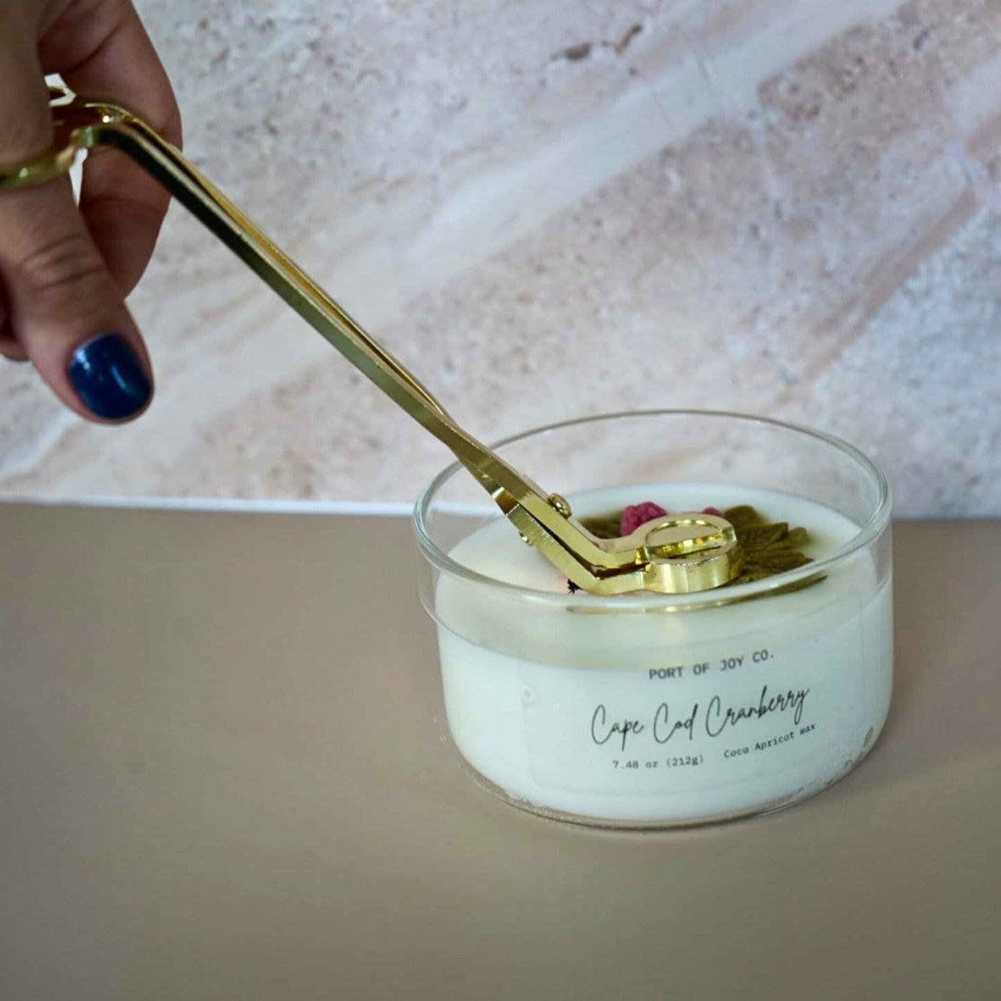 gold metal candle wick trimmer stainless steel luxury finish. being used in the image